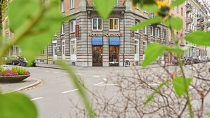 A hotel with a classic facade, a sign reading "HOTEL ST. GEORGES," and a street view with parked cars and a roundabout. - Saint Georges Hotel (Zürich)