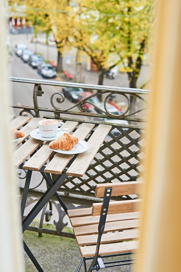 A wooden outdoor table with a croissant and a cup of coffee. - Saint Georges Hotel (Zürich)