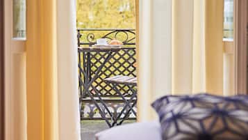 A view through a doorway to an outdoor balcony with a table, a chair, and a railing.