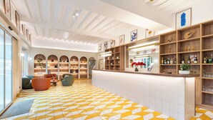 A hotel lobby with a geometric patterned floor, a reception desk, and a seating area with sofas.