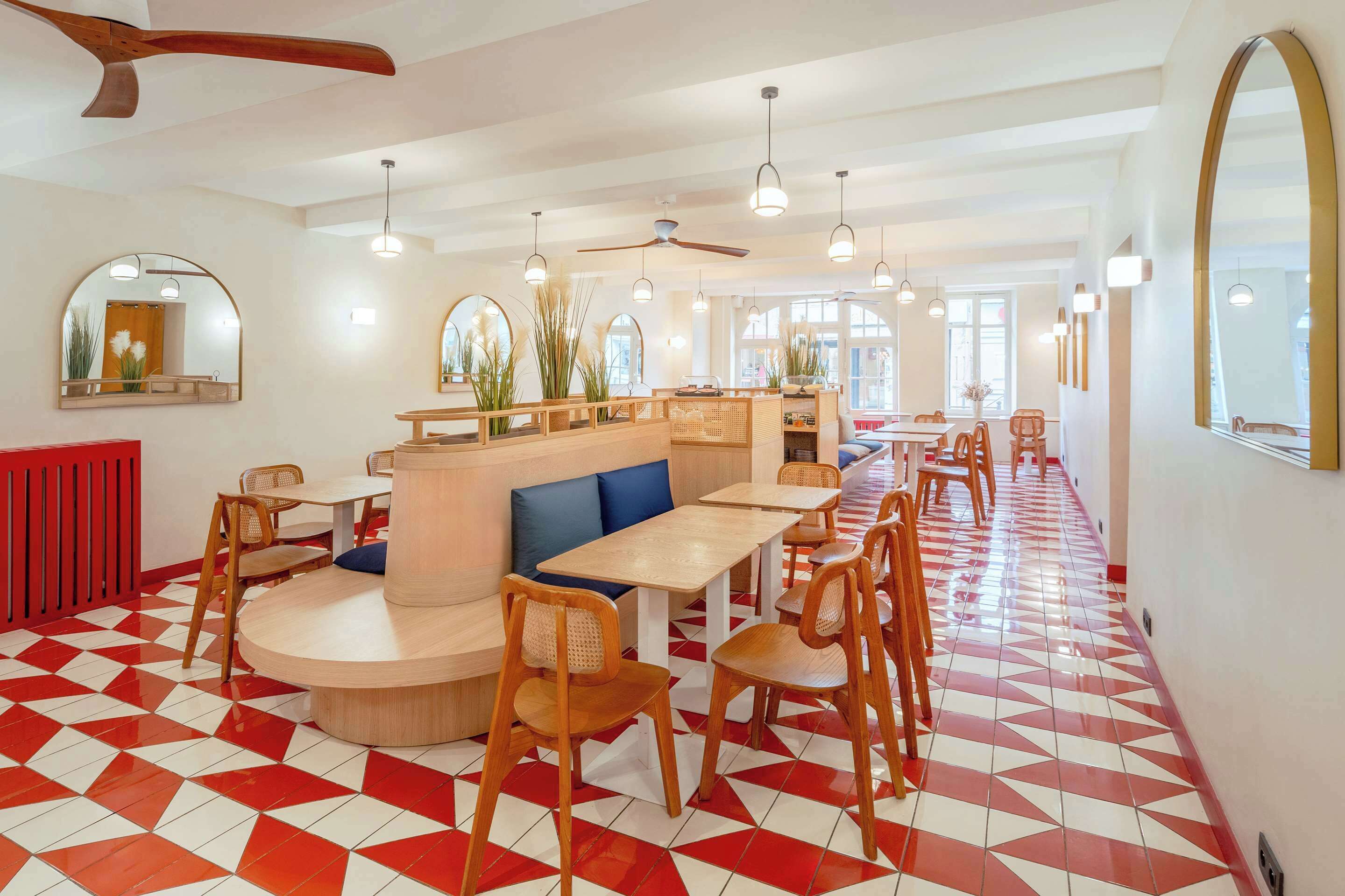 Un restaurante con suelo de patrón geométrico, muebles de madera e iluminación colgante.