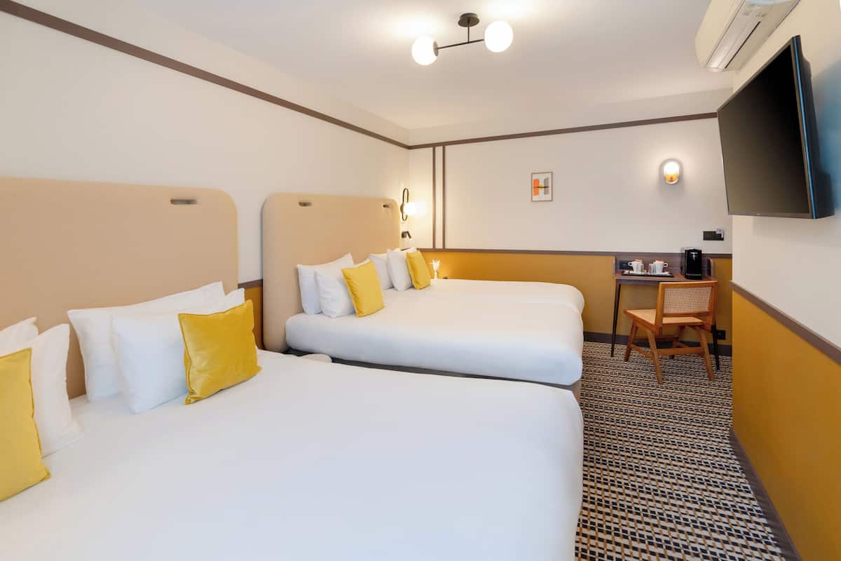 Une chambre d’hôtel avec deux lits, un bureau, une chaise, une télévision et une machine à café.