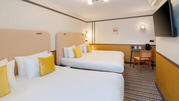Habitació d'hotel amb dos llits, un escriptori, una cadira, un televisor i una cafetera.