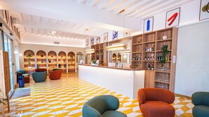 A modern lobby with a geometric patterned floor, a reception desk, and seating areas.