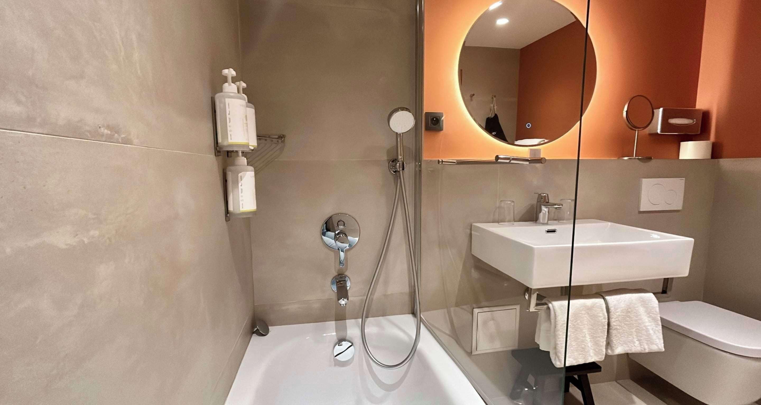 Ein modernes Badezimmer mit einer Duschkabine aus Glas, einem weißen Waschbecken und einer Toilette.