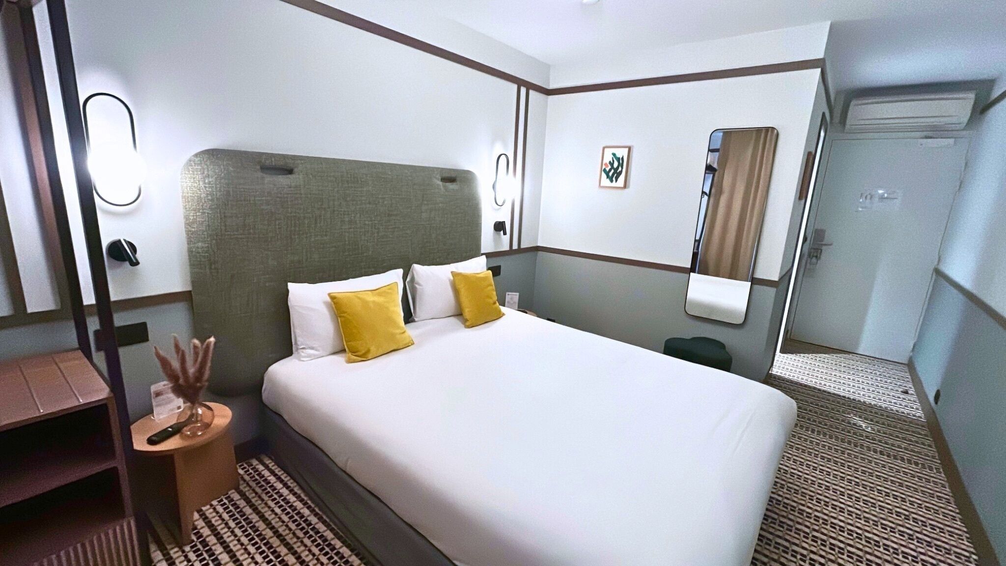 Een hotelkamer met een groot bed, nachtkastjes, een bureau en een spiegel.