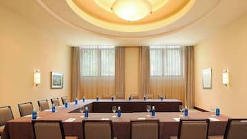 Un salón de conferencias con una larga mesa, sillas y una araña.