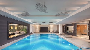 Una piscina interior de diseño moderno, con luces de techo en forma de hoja y vista despejada del área de la piscina.