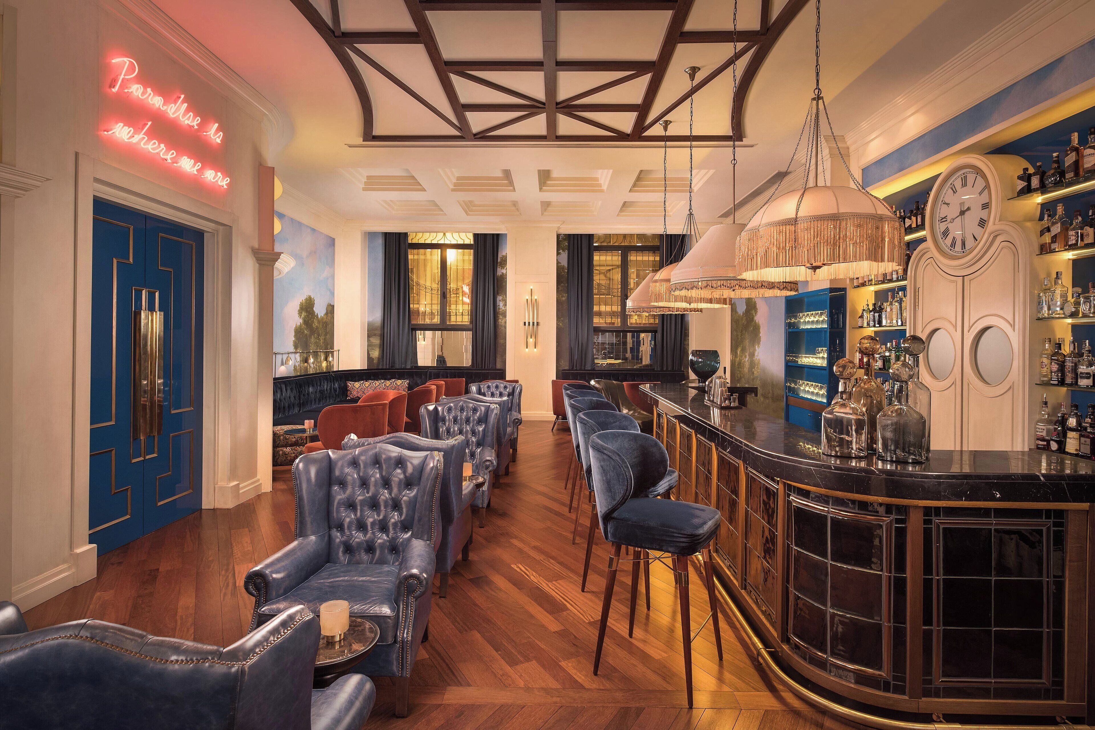 A bar area with leather chairs, a bar counter, and a neon sign.