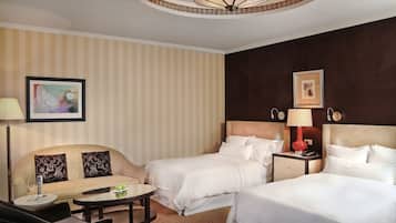 Habitación de hotel con dos camas, un sofá, una mesa redonda y una lámpara.