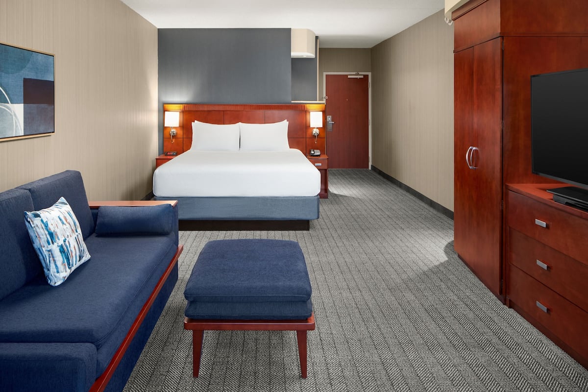 A hotel room with a bed, a sofa, a TV, and a desk.