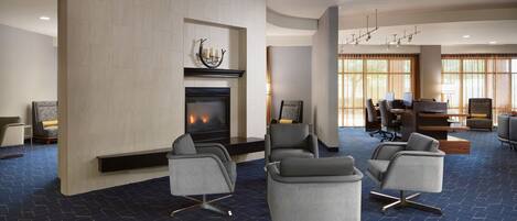 A modern lobby with a fireplace, comfortable seating, and large windows.