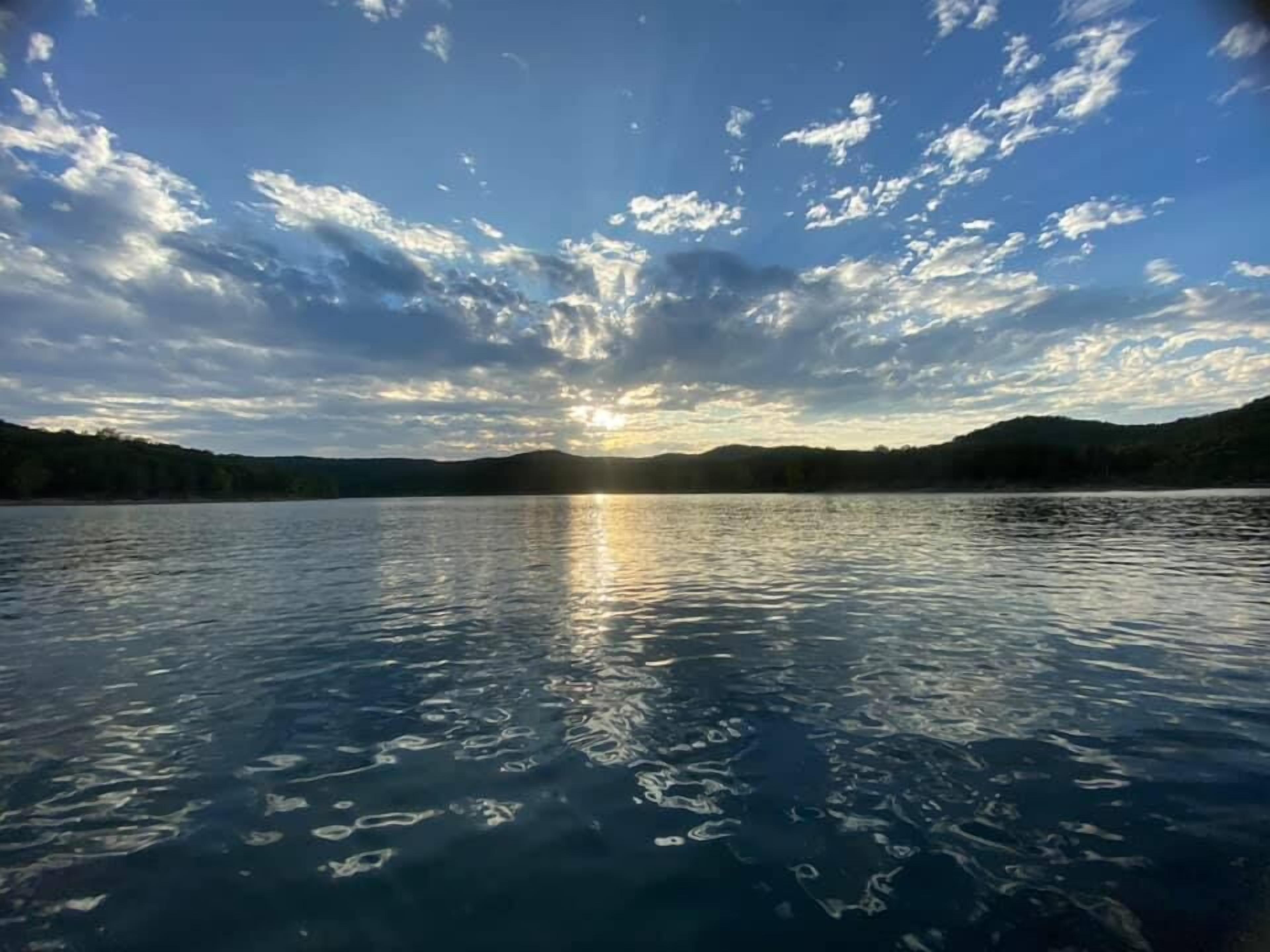 Un lago tranquilo con cielo despejado y reflejos de luz solar en el agua.