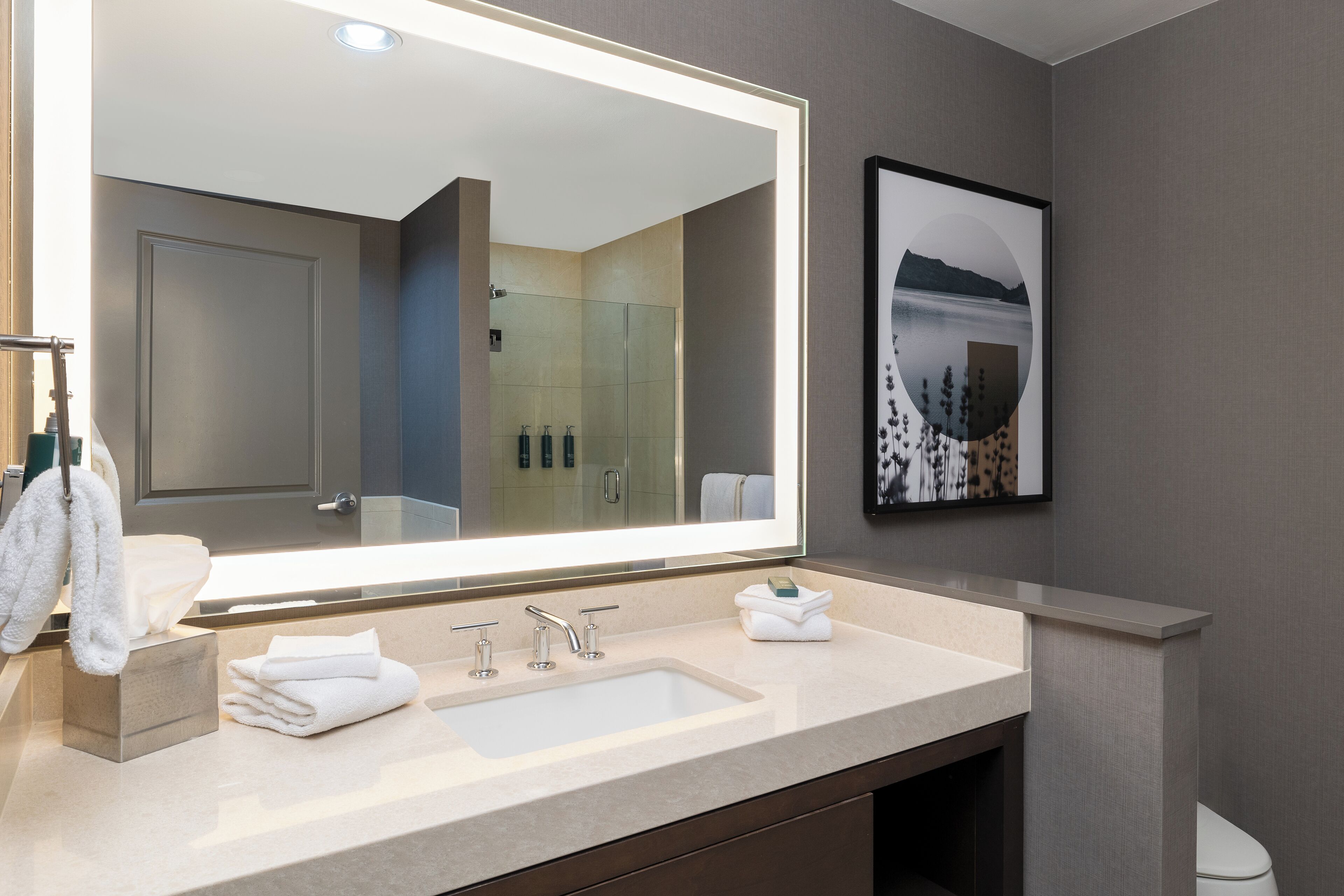 Un baño moderno con un espejo grande, un lavabo e inodoro.