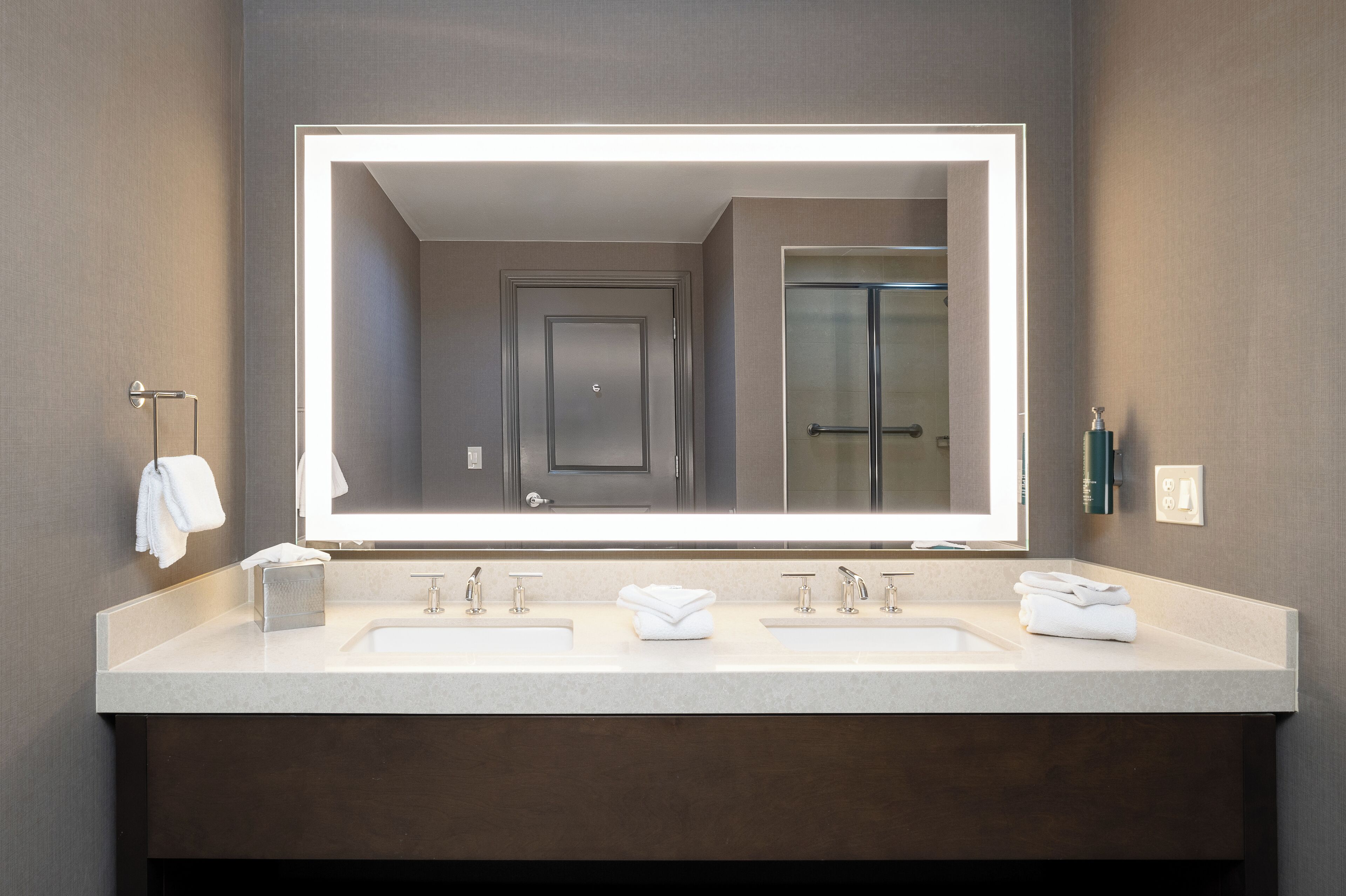 A modern bathroom with two sinks, a large mirror, and a glass shower.