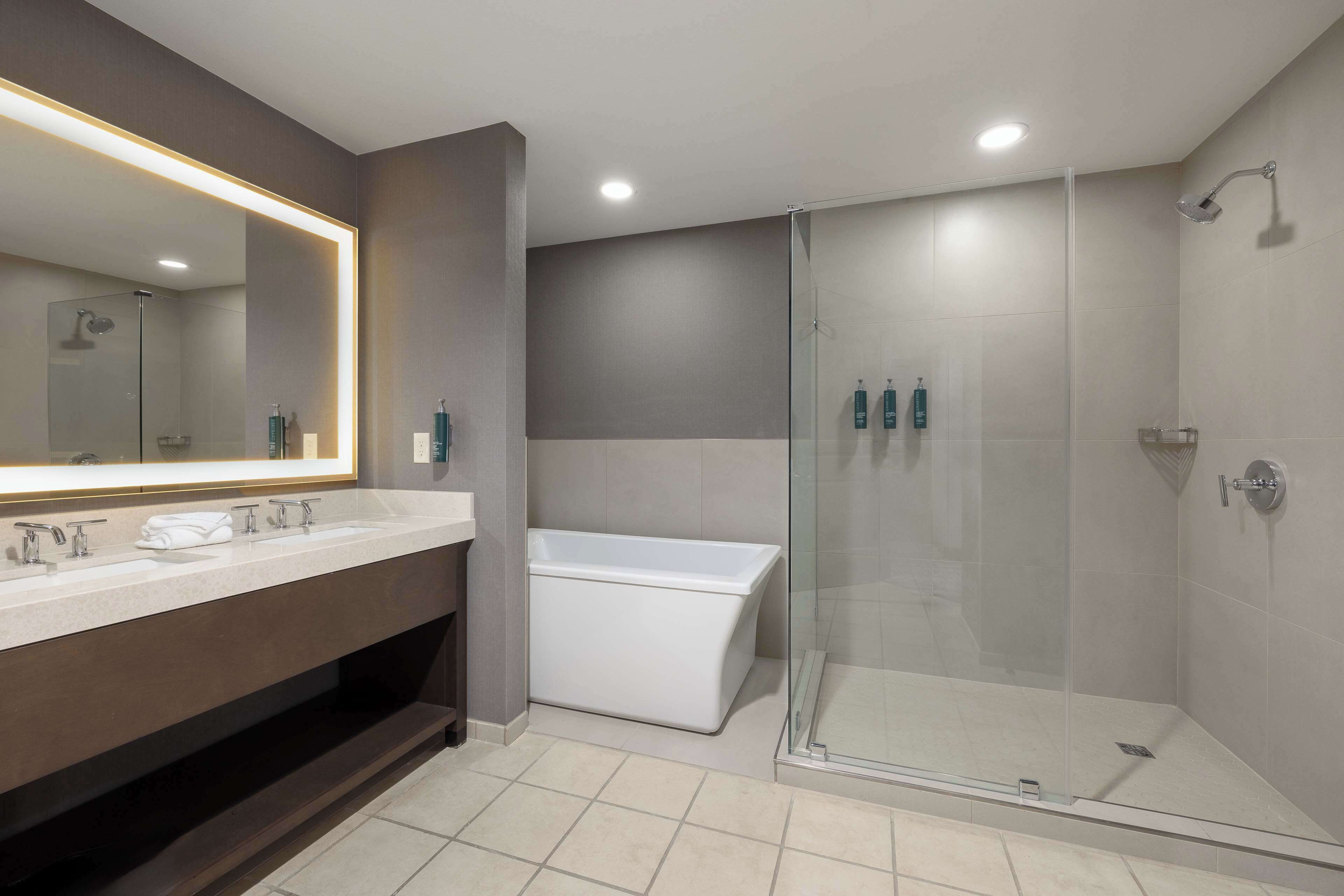 A modern bathroom with a large mirror, a bathtub, and a glass-enclosed shower.