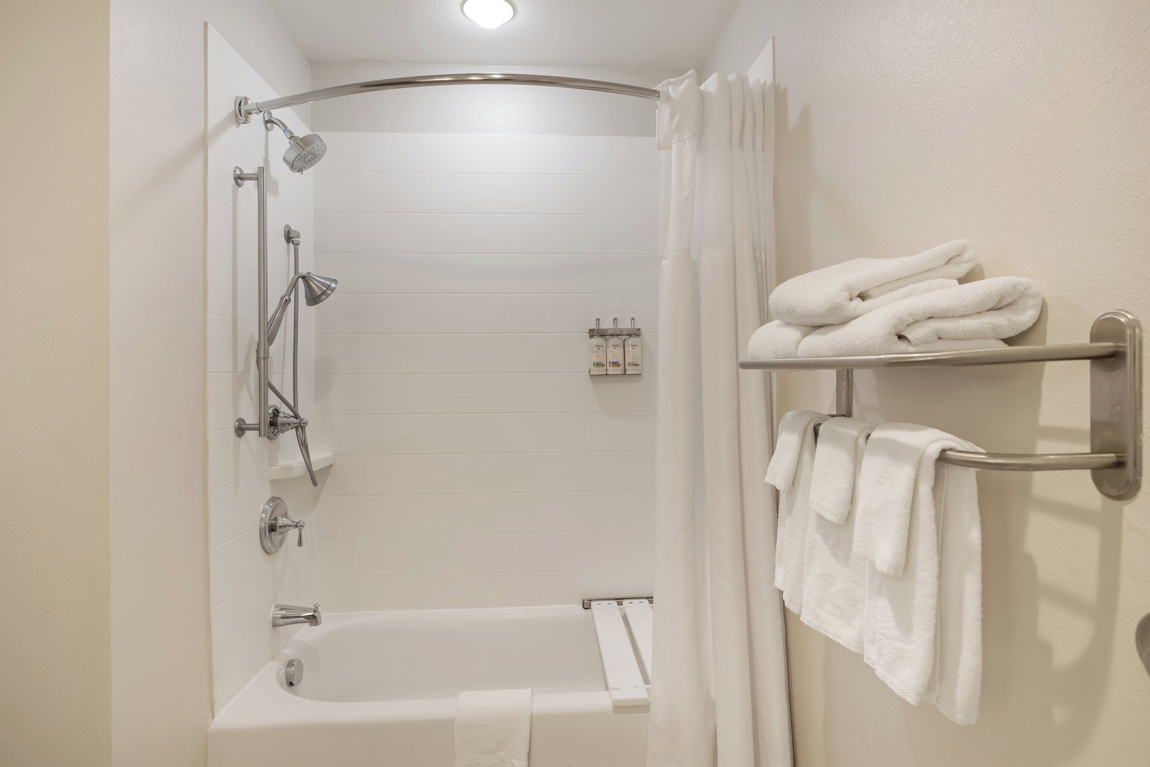 Ein Badezimmer mit einer Badewanne, einer Dusche und einem Handtuchhalter mit Handtüchern.