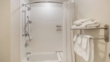 Ein Badezimmer mit einer Badewanne, einer Dusche und einem Handtuchhalter mit Handtüchern.