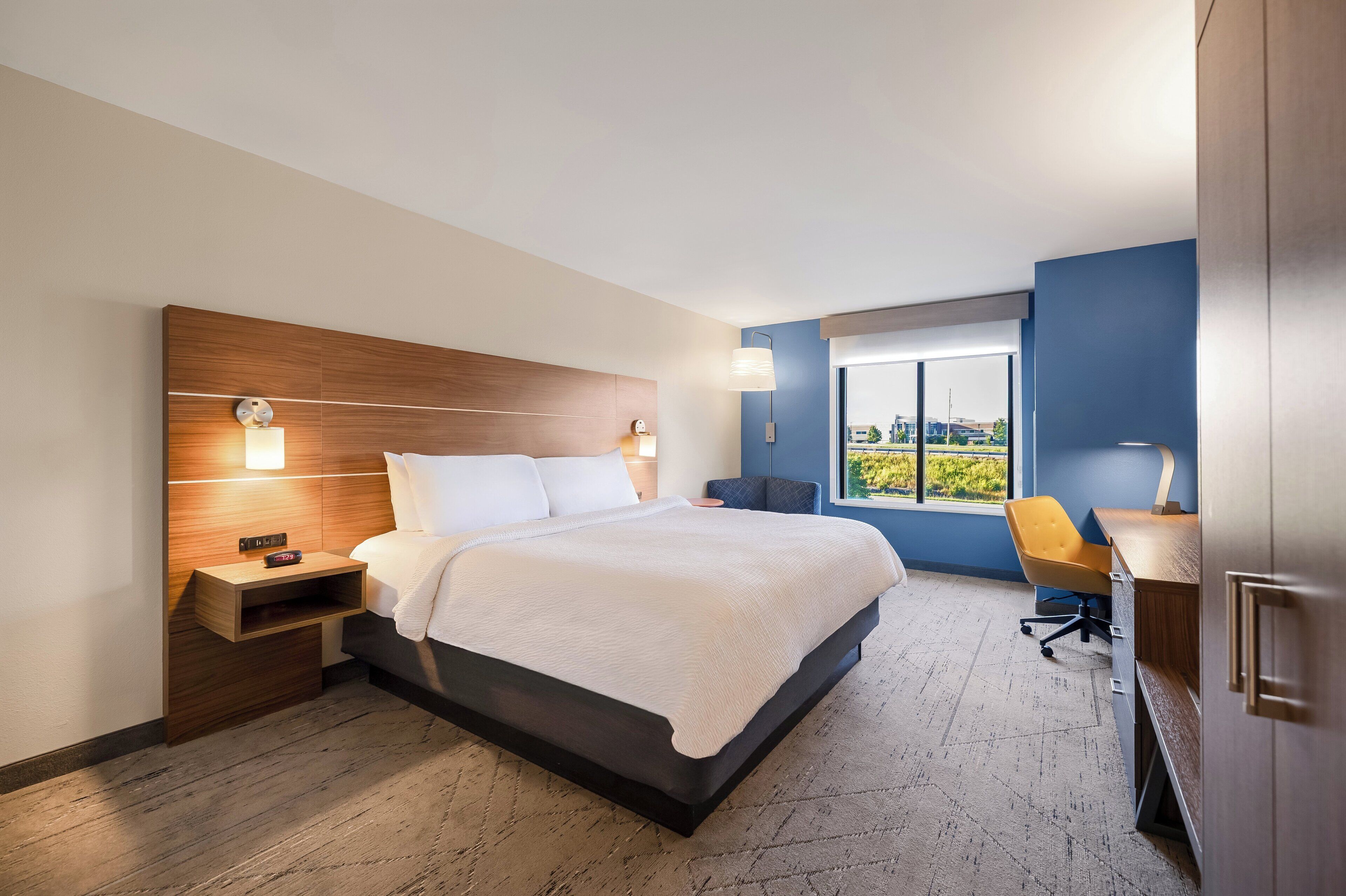 Ett modernt hotellrum med en stor säng, sängbord, ett skrivbord och ett fönster med utsikt.