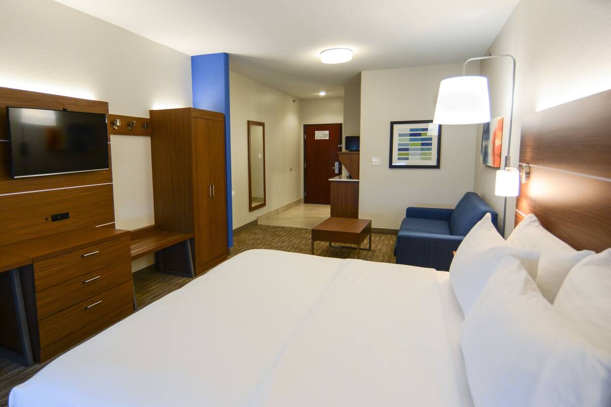 Une chambre d’hôtel avec un grand lit, une télévision, un bureau, une chaise et une lampe.