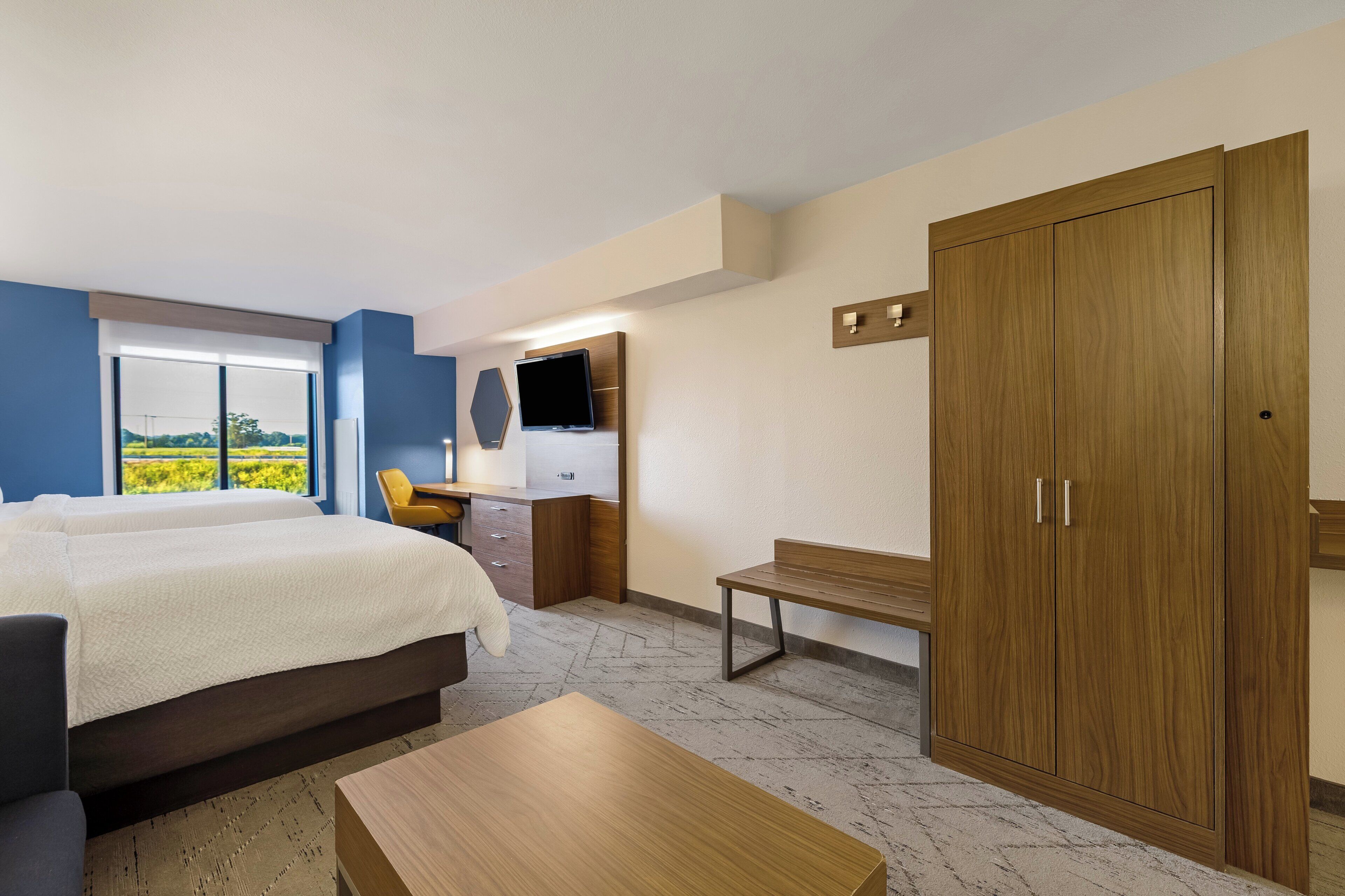 Una camera d'albergo con un letto, una scrivania, un armadio e una televisione.
