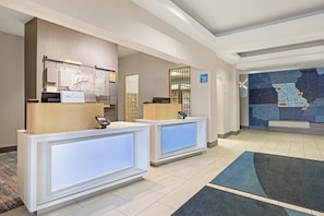A reception area with two counters, a map on the wall, and a sign indicating hotel services.