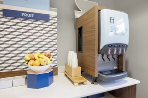 A fruit and juice station with a bowl of fruit, a juice dispenser, and a napkin holder. - Holiday Inn Express Hotel & Suites Rolla - U of Missouri S&T by IHG (Rolla)