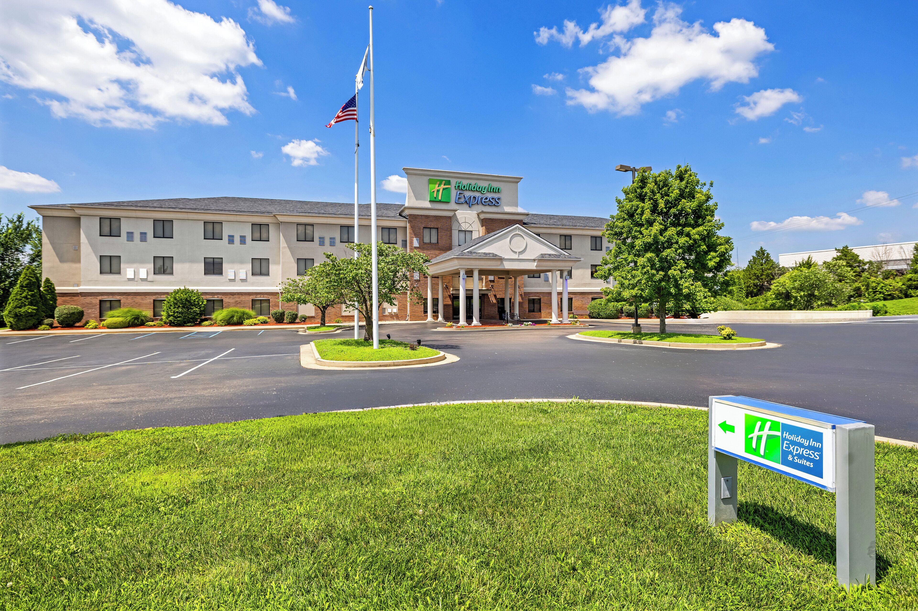 A Holiday Inn Express hotel with a central entrance, parking lot, and flagpole.