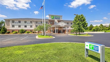 A Holiday Inn Express hotel with a central entrance, parking lot, and flagpole.