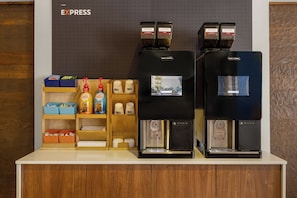A coffee station with two espresso machines, labeled 'Costa Coffee,' and a display of coffee beans and branded items.