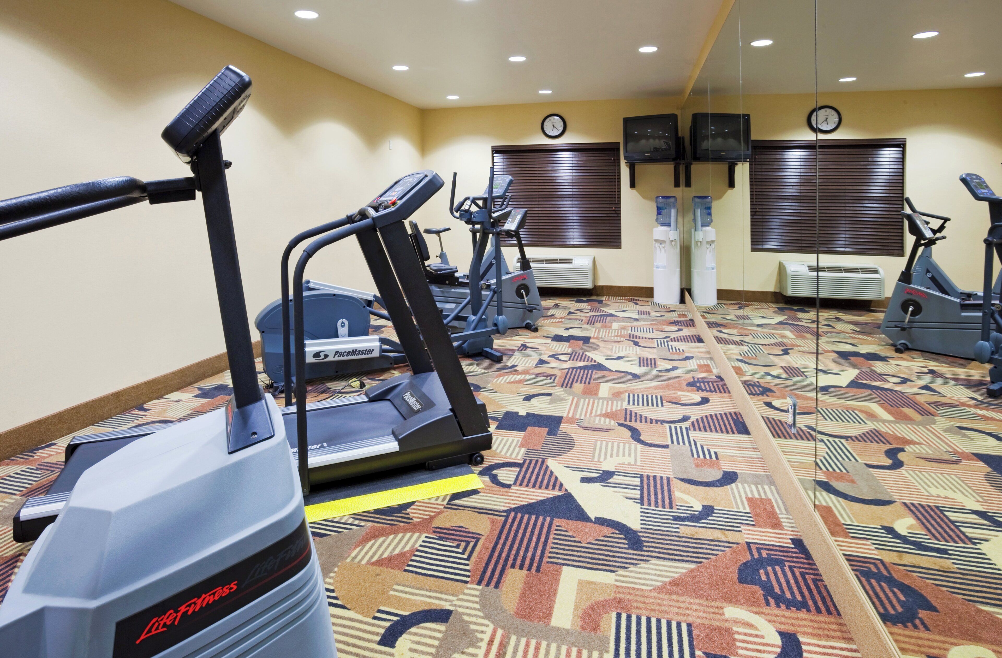 A fitness center with treadmills, stationary bikes, and a patterned carpet.