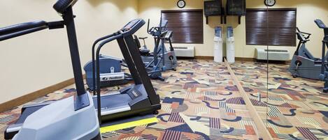 A fitness center with treadmills, stationary bikes, and a patterned carpet.