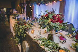 Uma longa mesa de banquete com arranjos florais e velas.