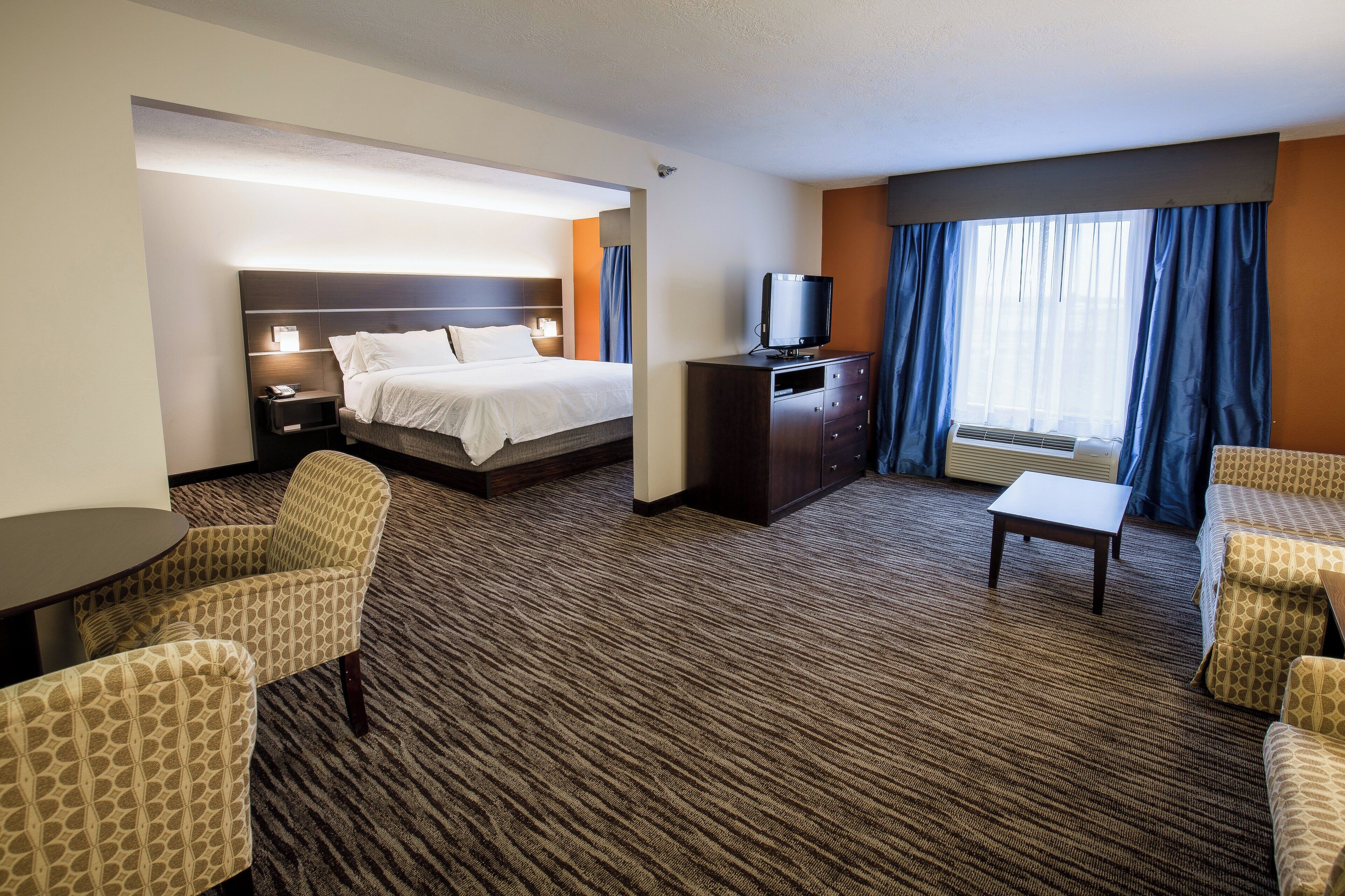 Une chambre d’hôtel équipée d’un lit, d’un bureau, d’une chaise, d’une télévision et d’une fenêtre avec des rideaux.