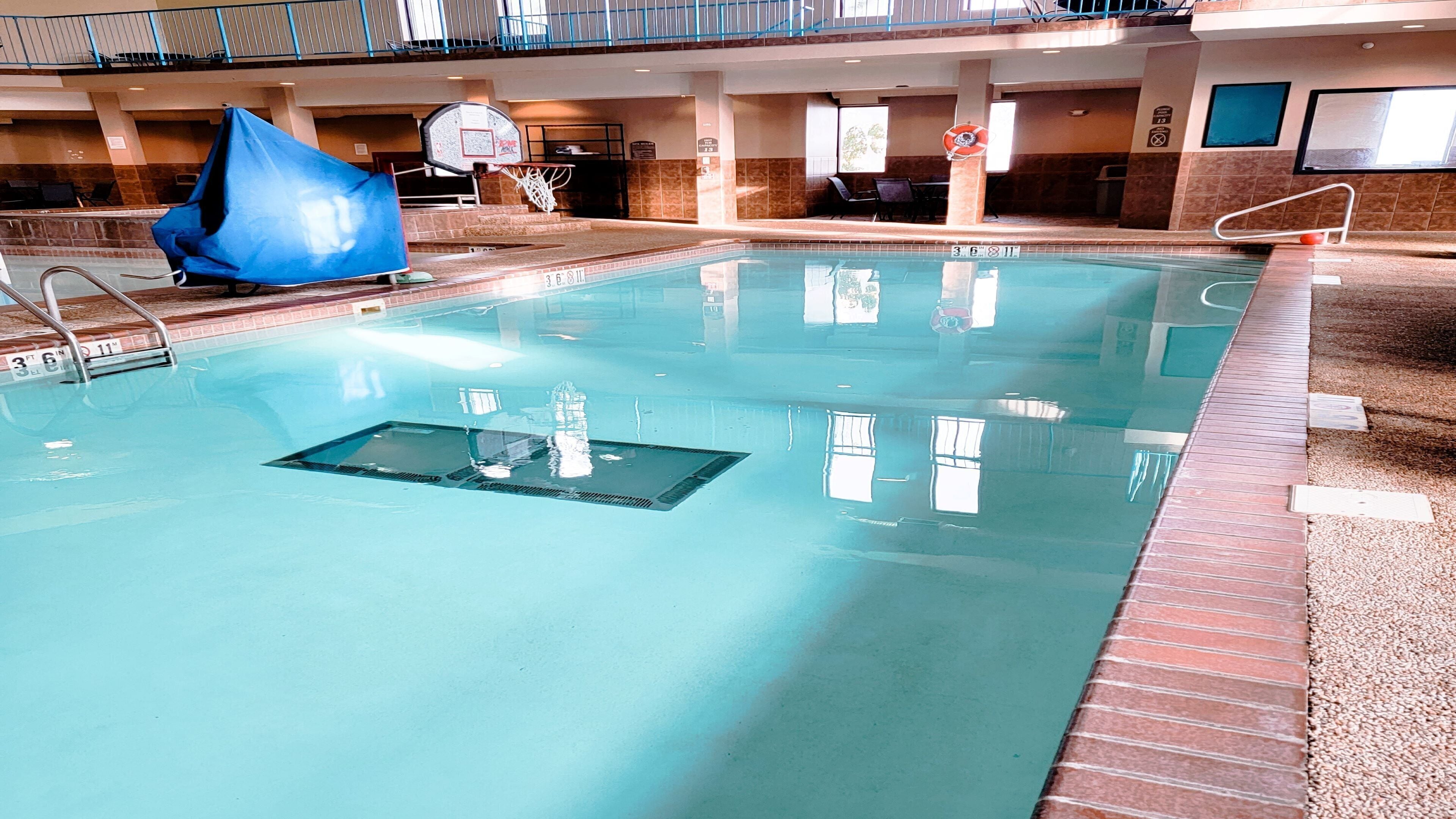 An indoor swimming pool with a diving board, a basketball hoop, and a lifebuoy.