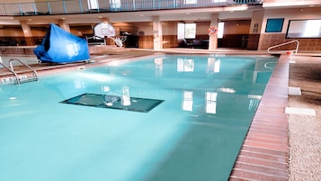 Piscina interna com trampolim, cesta de basquete e boia salva-vidas.