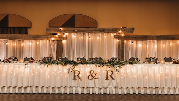 A banquet table with a white tablecloth, adorned with greenery and the initials "R&R". - Holiday Inn Express & Suites Brandon by IHG (Brandon)