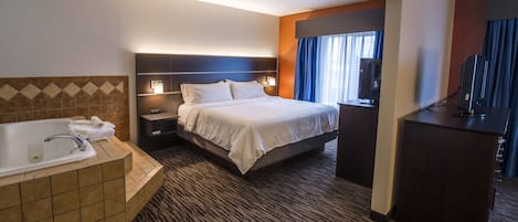 Habitación de hotel con una cama grande, baño independiente con bañera, escritorio y televisión.