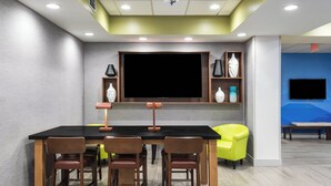 A conference room with a large flat-screen TV, wooden chairs, a black table, and a bright yellow chair. - Holiday Inn Express Bartow by IHG (Bartow)