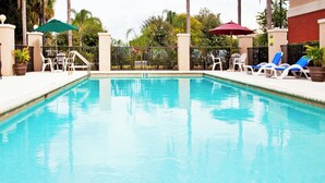 A swimming pool with a clear blue water surface, surrounded by lounge chairs and umbrellas. - Holiday Inn Express Bartow by IHG (Bartow)