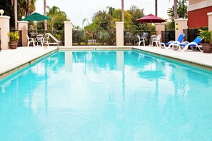 A swimming pool with lounge chairs and umbrellas.