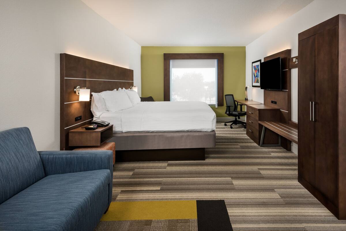 A hotel room with a bed, a desk, a TV, and a sofa.