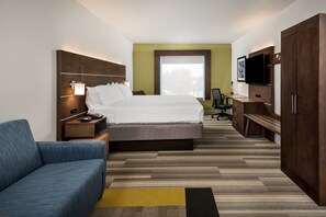 A hotel room with a bed, a desk, a TV, and a sofa.