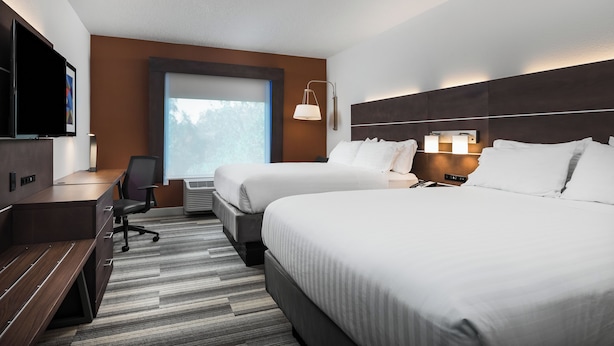 A hotel room with two beds, a desk, a chair, a TV, and a window with a view of trees. - Holiday Inn Express Bartow by IHG (Bartow)