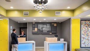 A hotel reception area with two reception desks, a modern chandelier, and a wall-mounted sign. - Holiday Inn Express Bartow by IHG (Bartow)