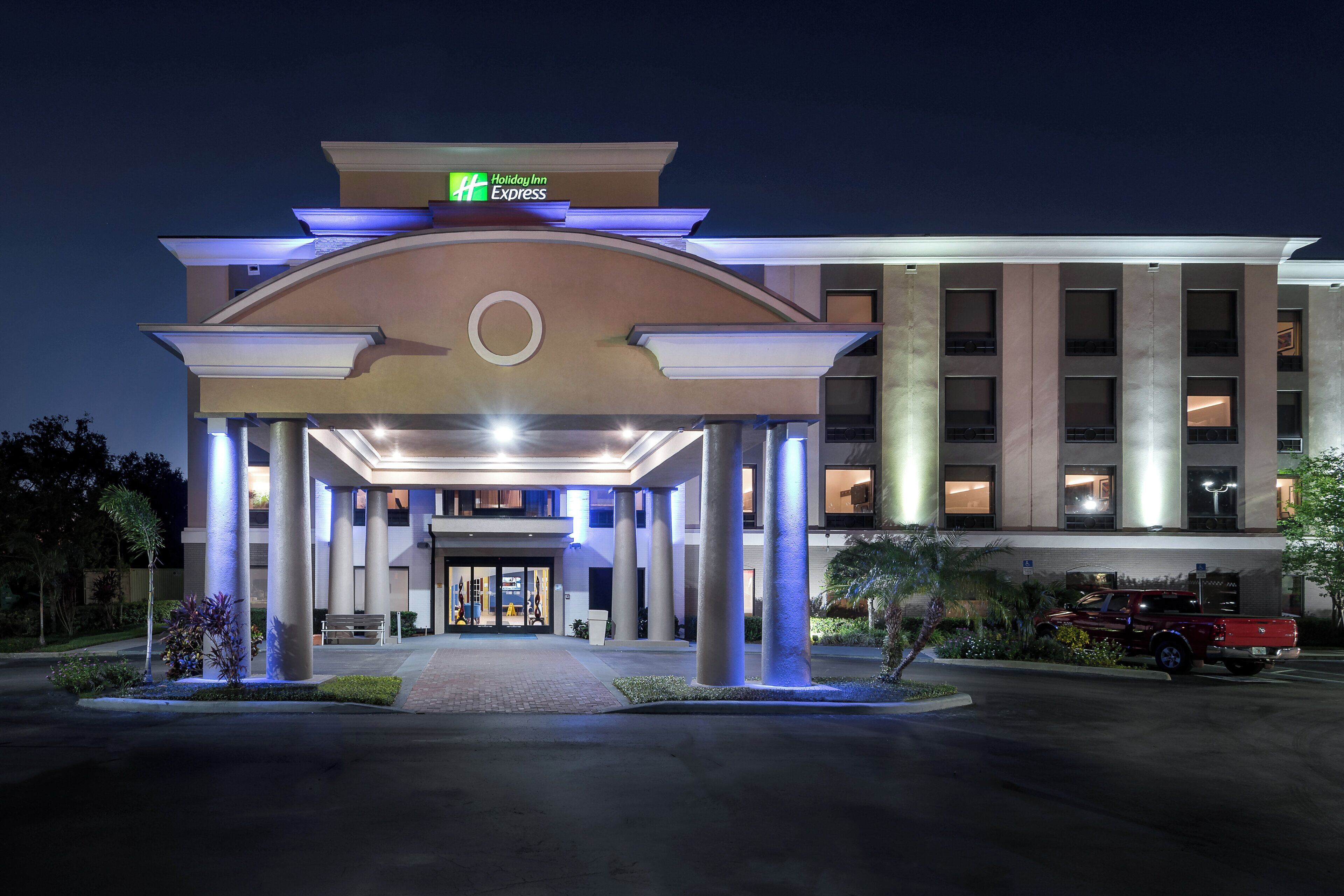 A Holiday Inn Express hotel entrance with a covered walkway, columns, and a parking area.