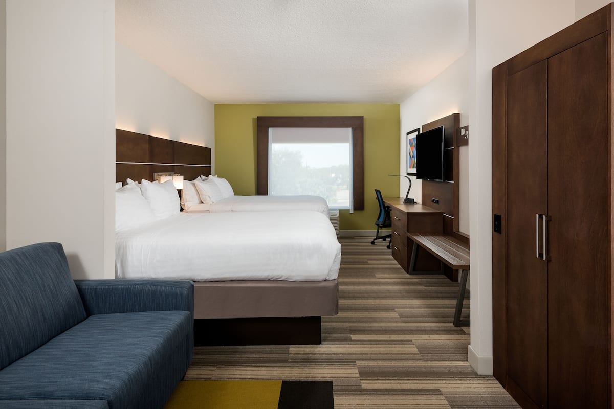 A hotel room with a large bed, a sofa, a TV, and a wardrobe.