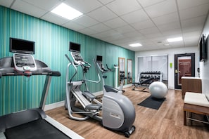 A gym with treadmills, elliptical machines, a stationary bike, and a large exercise ball.