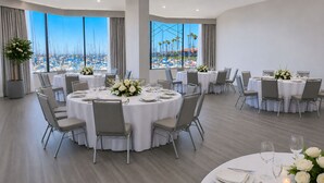Un comedor amplio con mesas redondas, sillas y ventanas grandes que dan a un puerto deportivo.