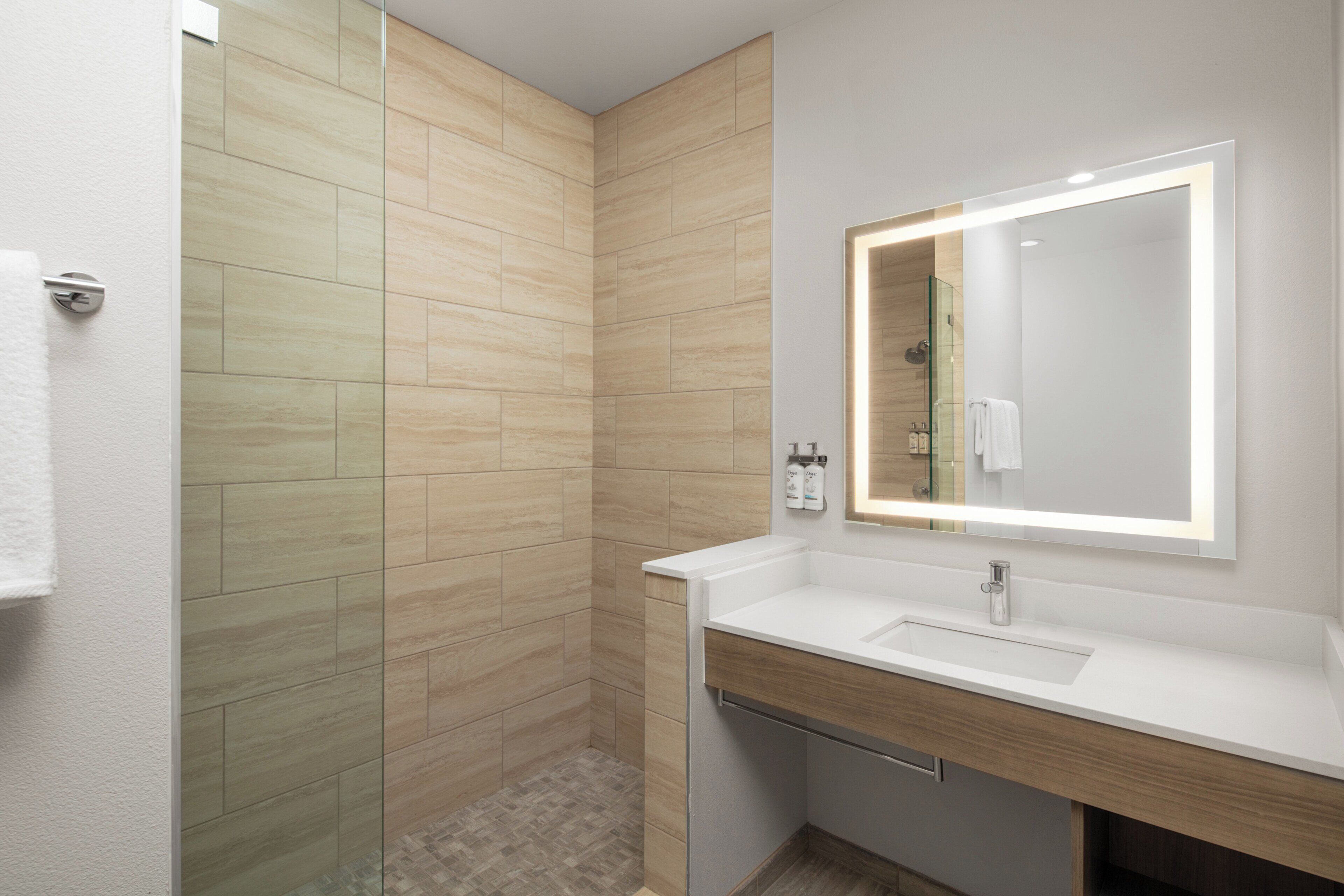 A modern bathroom with a shower, a sink, and a mirror.